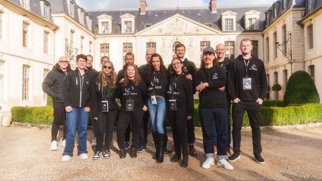 Photo de groupe portant des pulls Link Invest devant un chateau